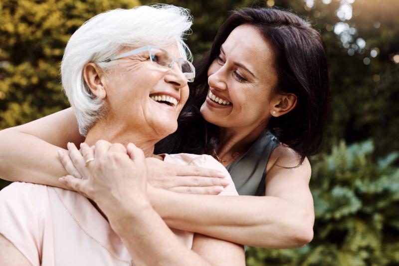An adult woman hugs her mother.
