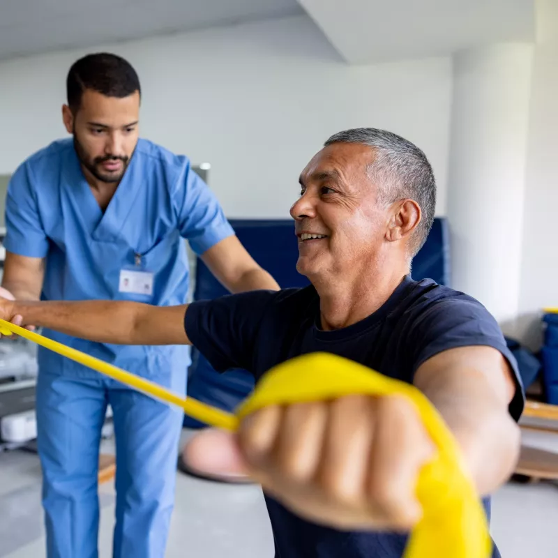 Physical therapy at a hospital with a therapist showing an older gentleman how to stretch