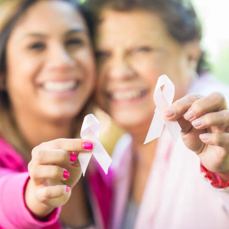 Mom and daughter wearing pink together, raising their pink ribbons