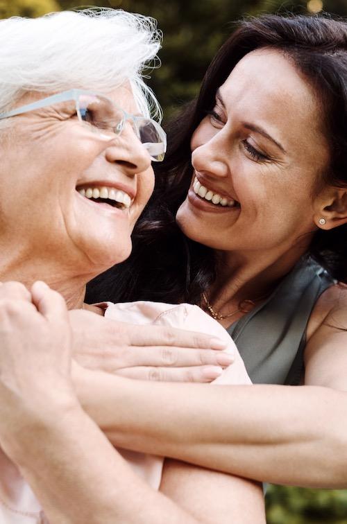 An adult woman hugs her mother.