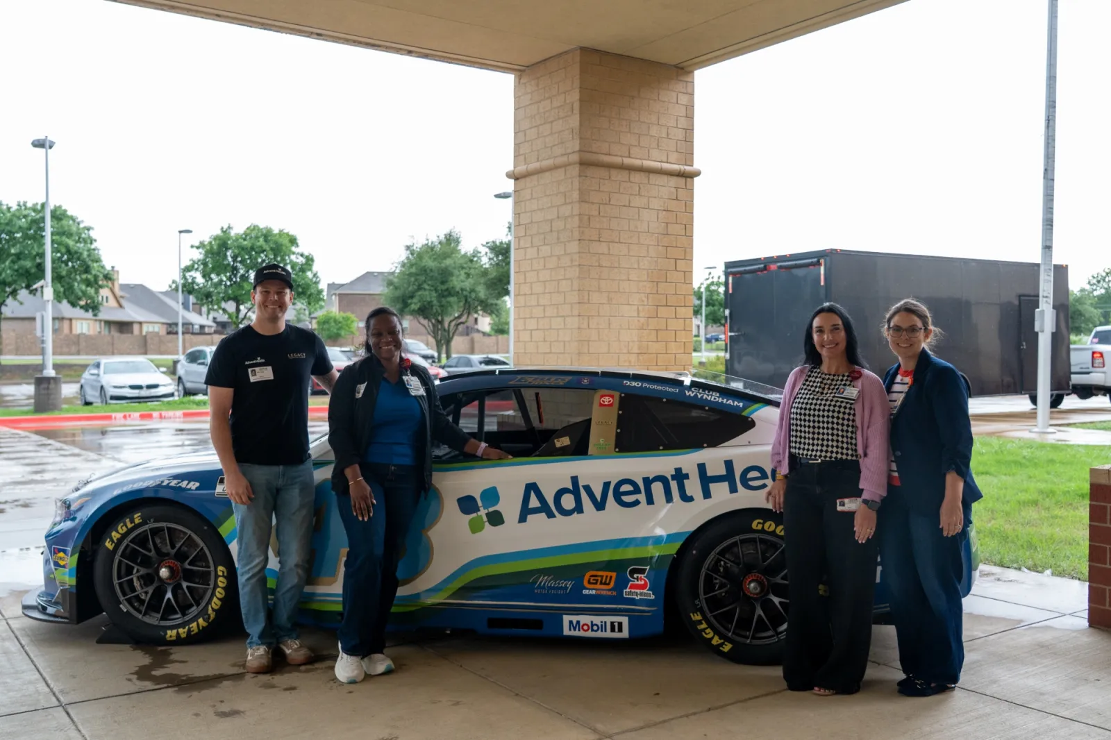 NASCAR driver and THM leadership standing in front of the race car